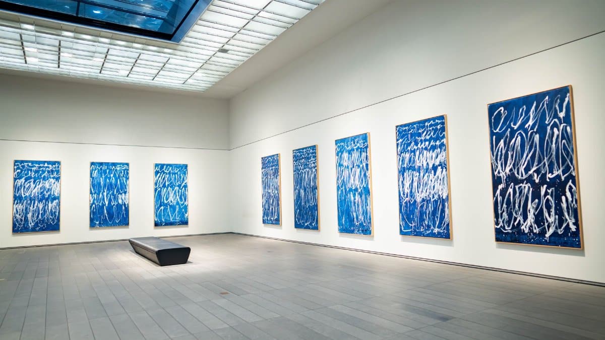 Spacious modern art gallery featuring a collection of blue abstract paintings on display.