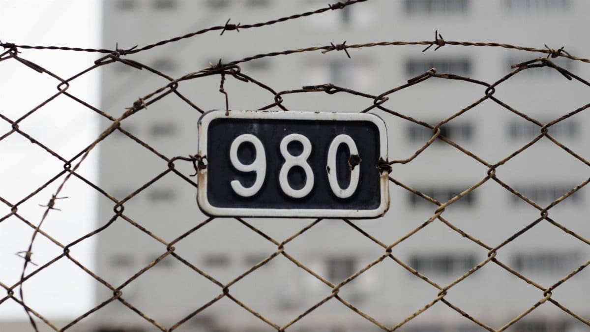 Close-up of a barbed wire fence with a metal number plate. Symbolizes security and restriction.