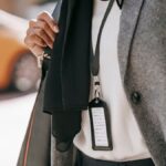 Crop unrecognizable female entrepreneur in formal outfit and name tag walking on city street on sunny day
