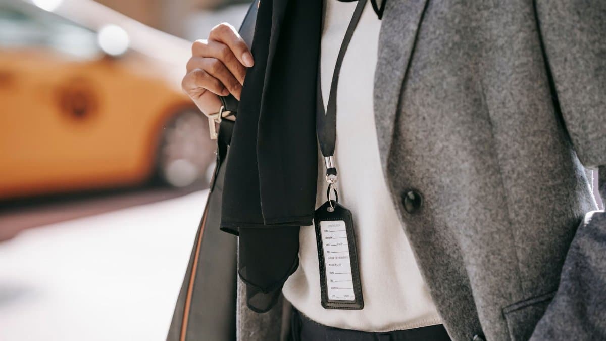 Crop unrecognizable female entrepreneur in formal outfit and name tag walking on city street on sunny day