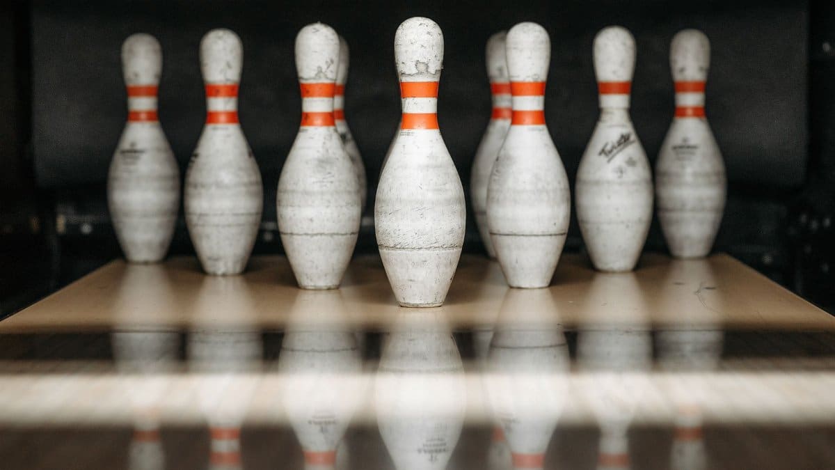 Focused close-up view of bowling pins lined up in an alley with reflections on the floor.