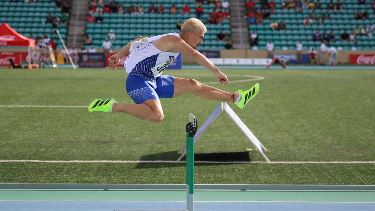 Dynamic shot of an athlete clearing a hurdle during an outdoor track event.
