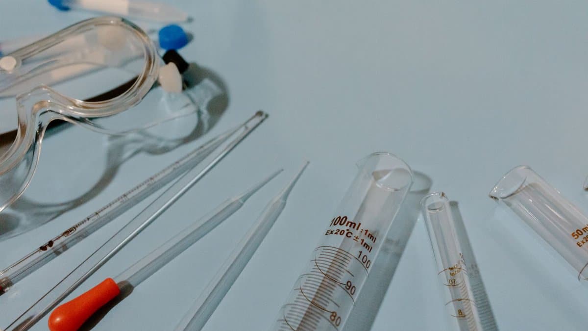 Detailed view of lab equipment like test tubes and goggles on a blue surface.