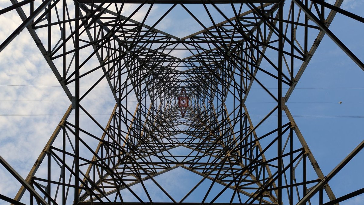Unique perspective looking up through a steel lattice tower against a blue sky.