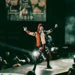 A vibrant luchador performs on stage in a lively wrestling event, thrilling a packed audience.