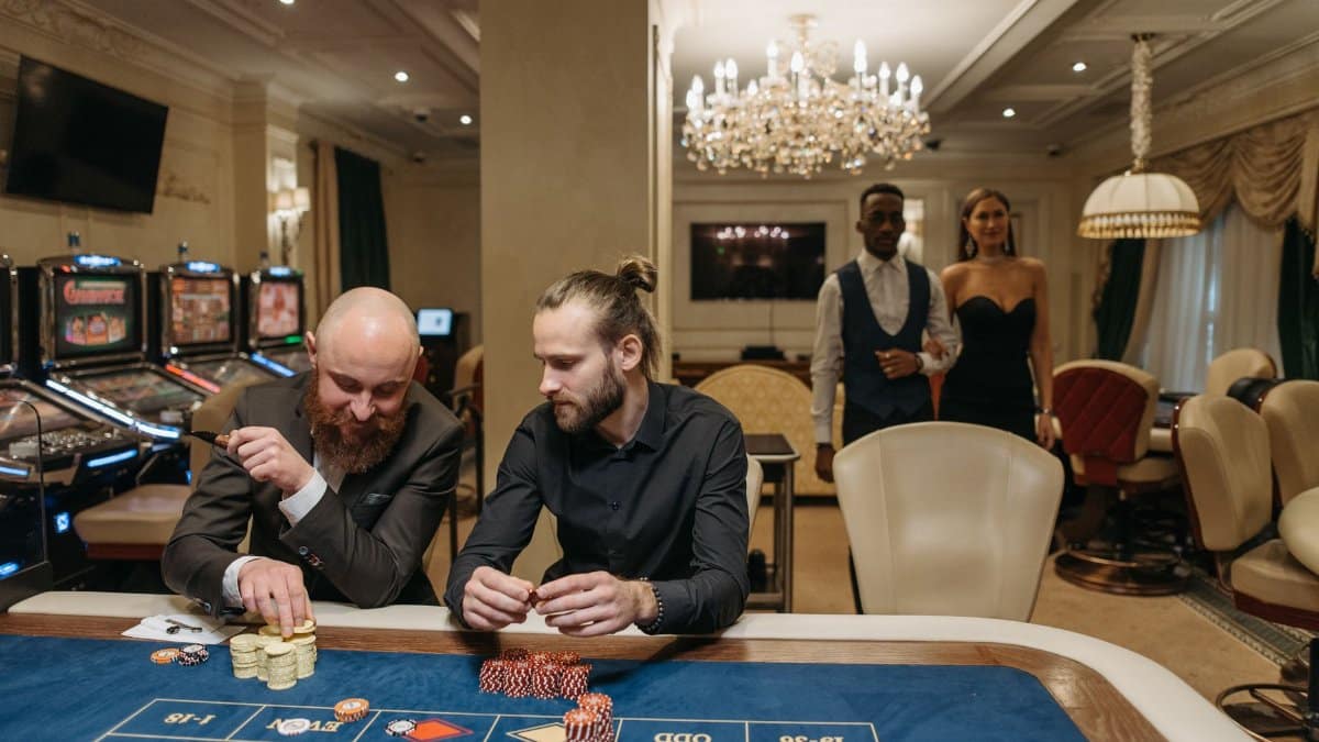 Elegant gamblers enjoy a night at the casino roulette table surrounded by luxury.