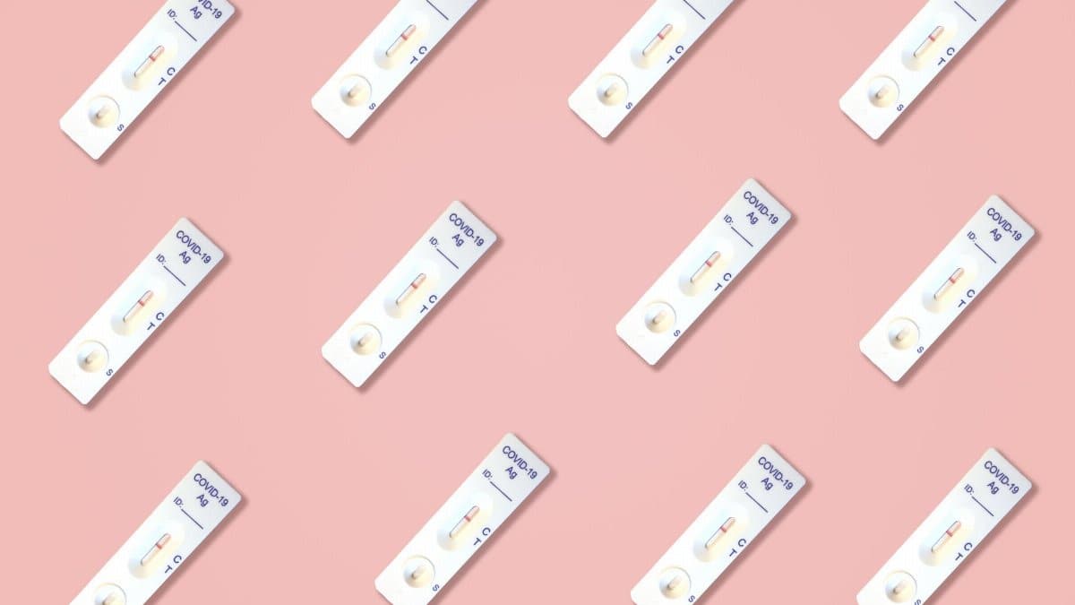 Multiple Covid-19 antigen test kits arranged on a pink surface, ideal for health-related content.
