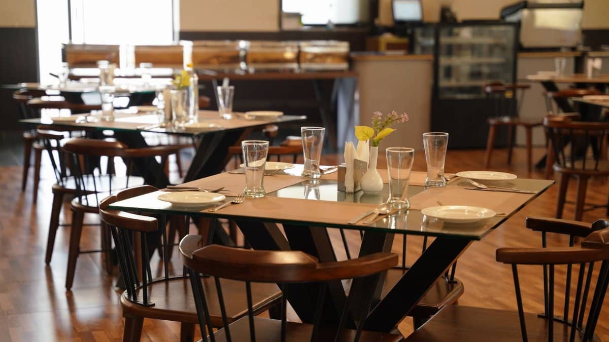 Spacious modern restaurant interior with elegant table settings and wooden decor, perfect for dining.