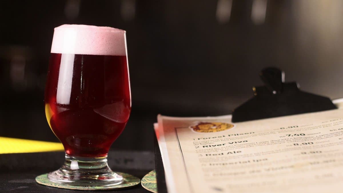 A stylish glass of dark ale on a table next to a bar menu, showcasing a cozy ambiance.