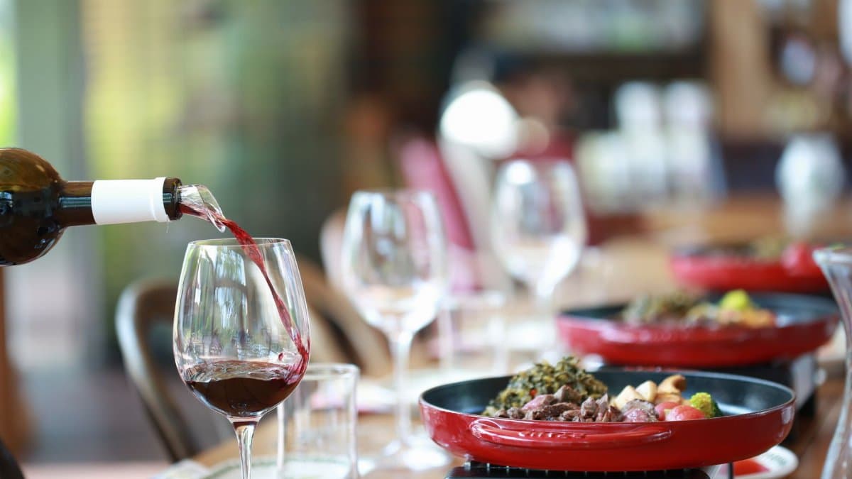 A sophisticated dining setup with red wine being poured into a glass. Perfect for gourmet lifestyle themes.