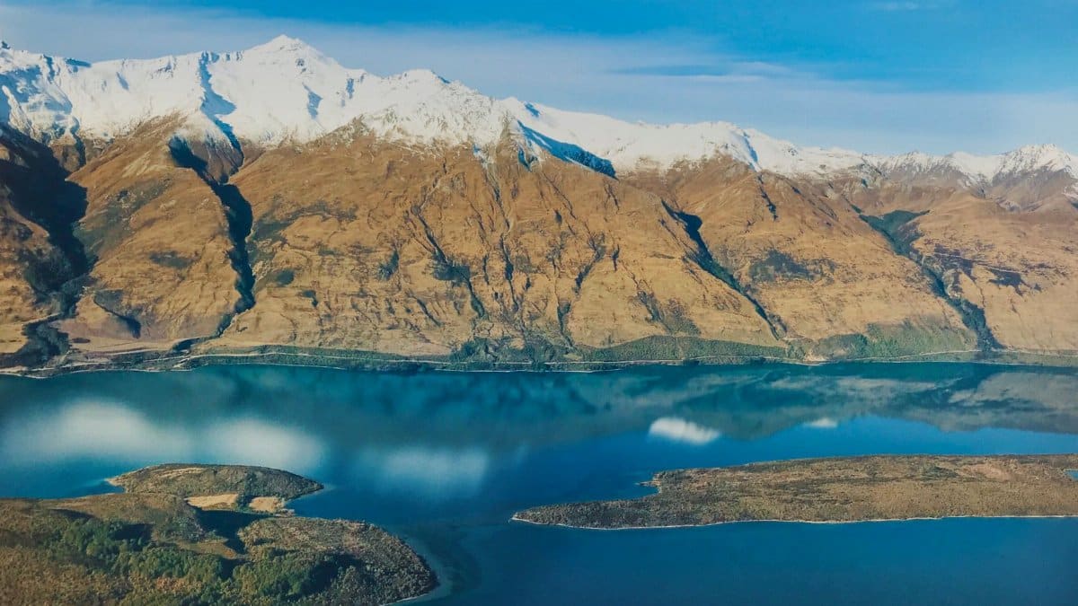 Scenic aerial shot of Lake Wakatipu with surrounding snow-capped mountains in Southland, New Zealand.