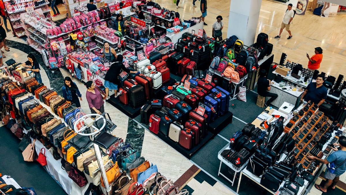 Overhead view of a vibrant shopping area in a Bangkok mall featuring purses, suitcases, and bustling shoppers.