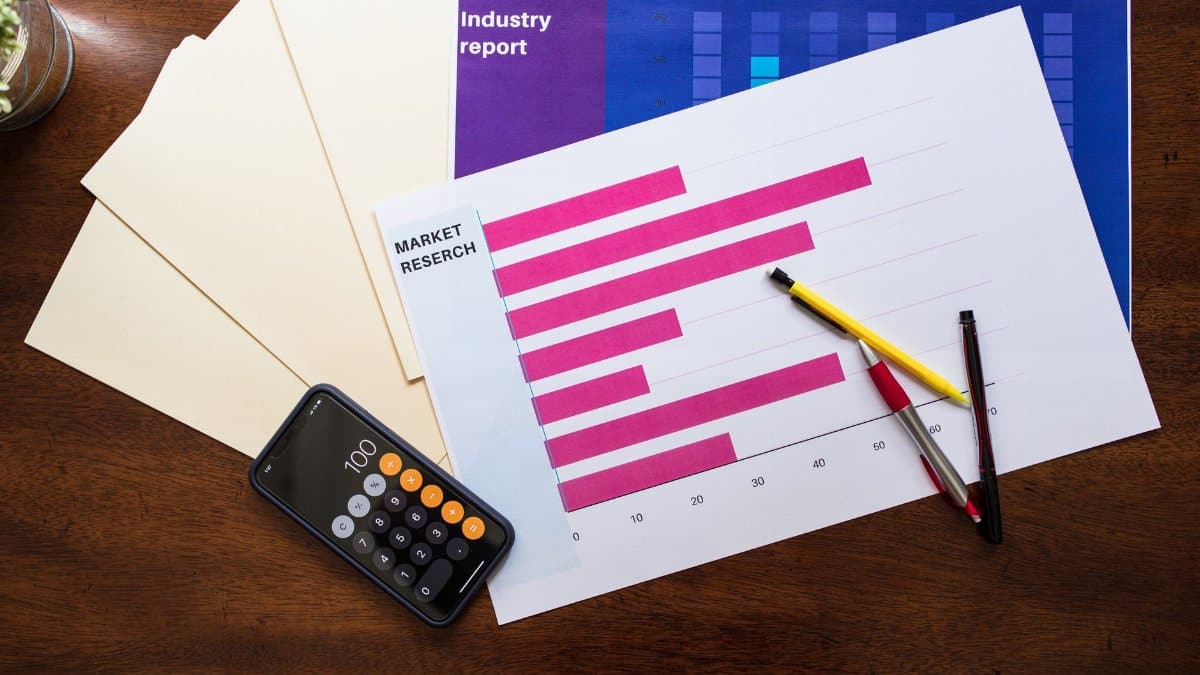 Top view of market research reports and calculator on a wooden desk, illustrating business analysis.