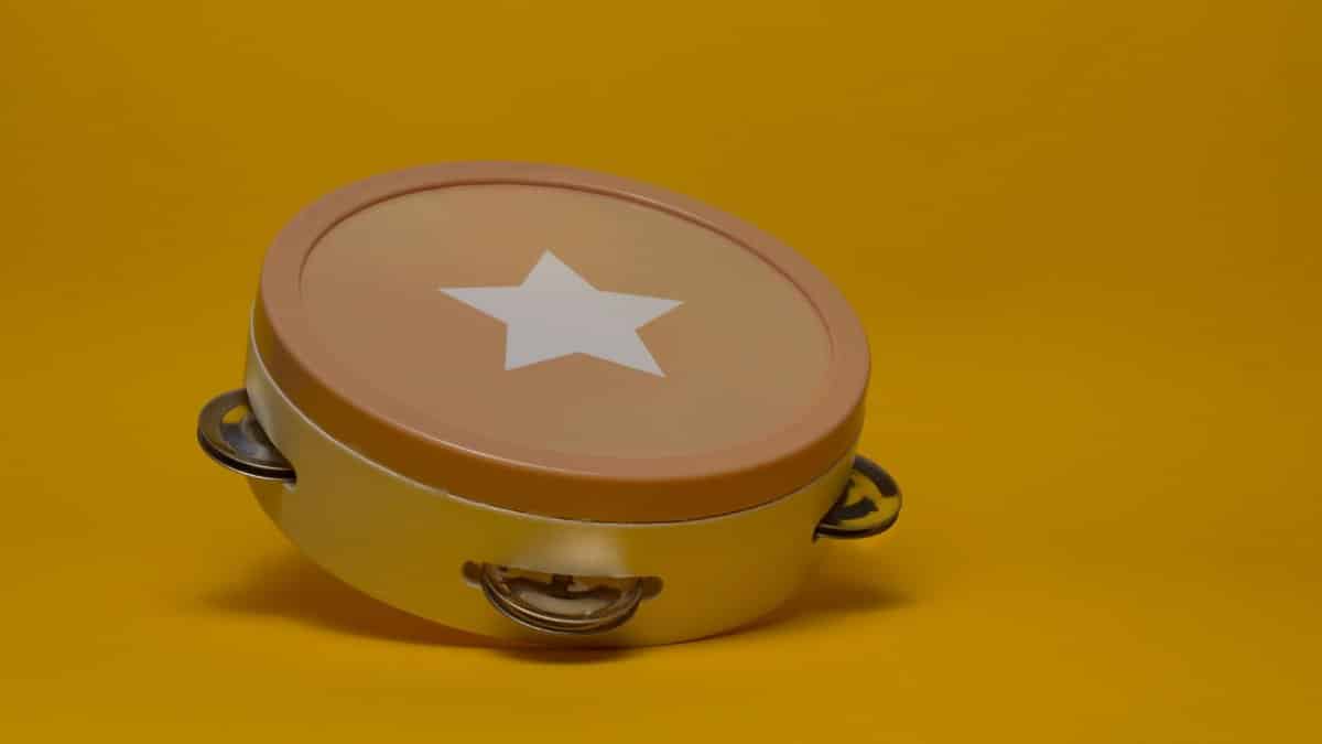 Vibrant tambourine featuring a star design sits against a bold yellow backdrop, perfect for music-themed designs.