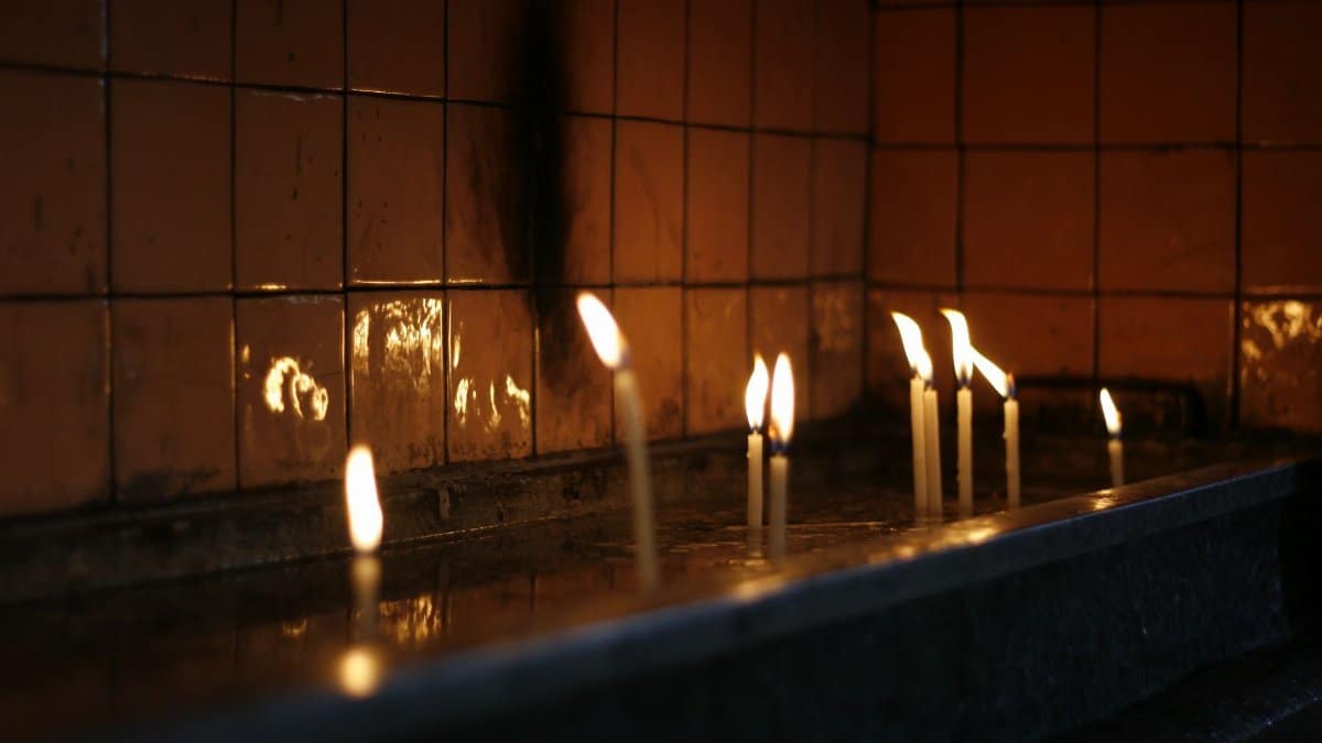 Softly glowing candles in a dimly lit environment create a calm and reflective mood.