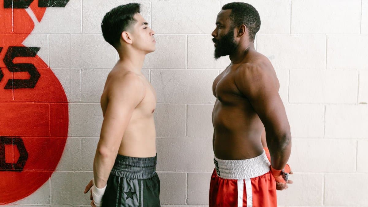 Two muscular boxers standing face-to-face in a gym, showcasing strength and determination.
