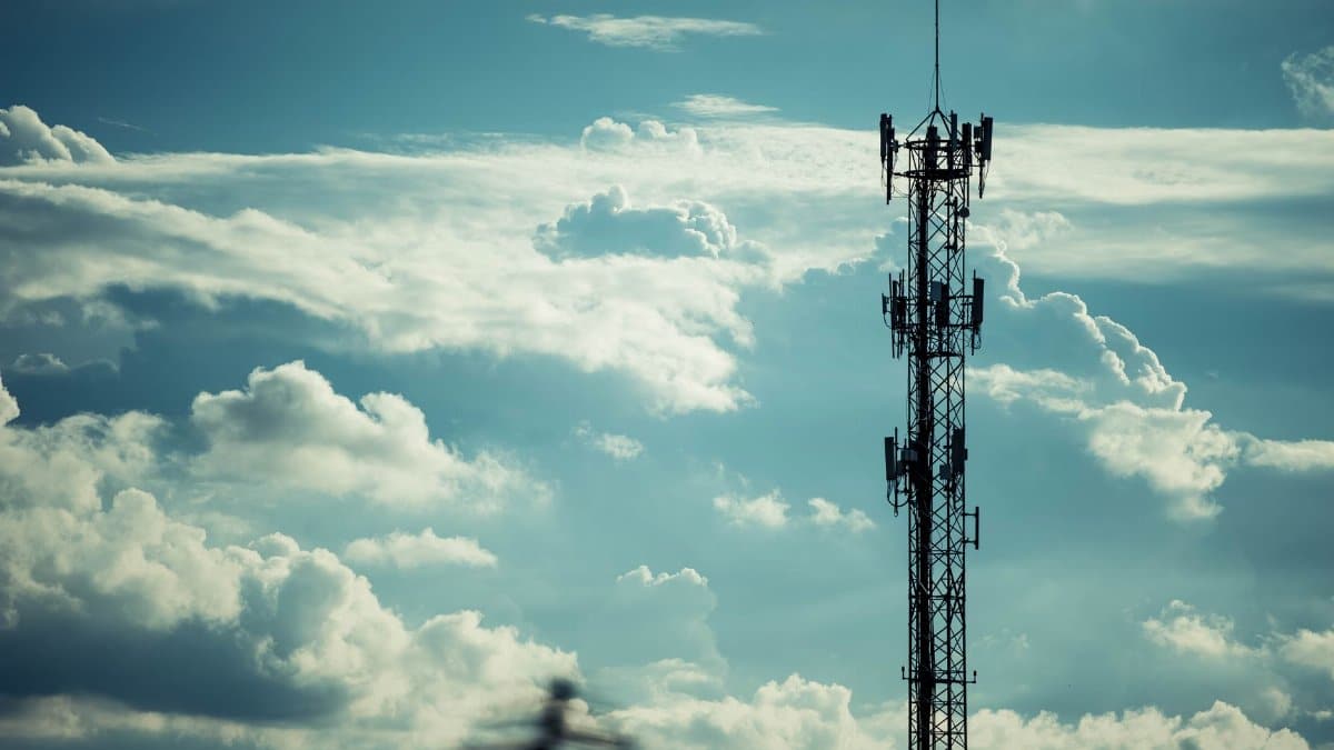 A tall communication tower silhouetted against a bright, cloudy sky, symbolizing connection.
