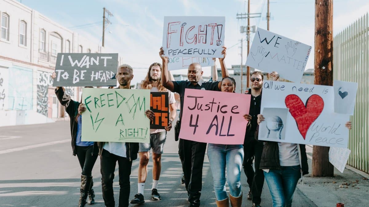 Group of activists hold signs advocating for justice and equality during a street protest.