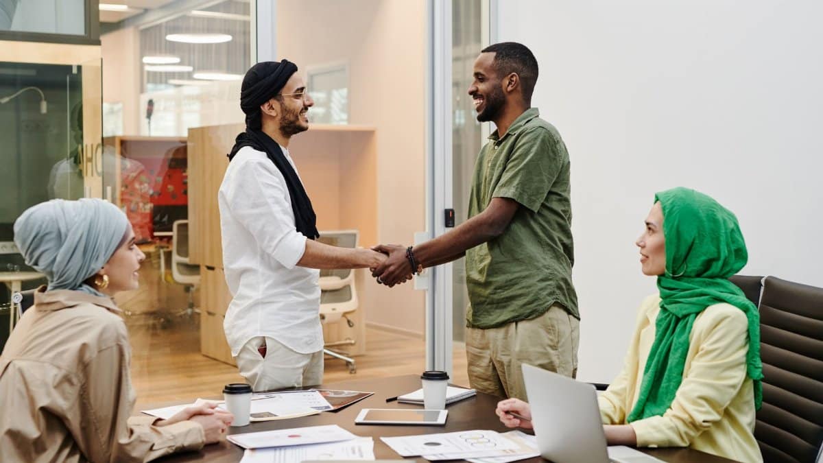A diverse team meeting in a modern office with people shaking hands, symbolizing teamwork and collaboration.