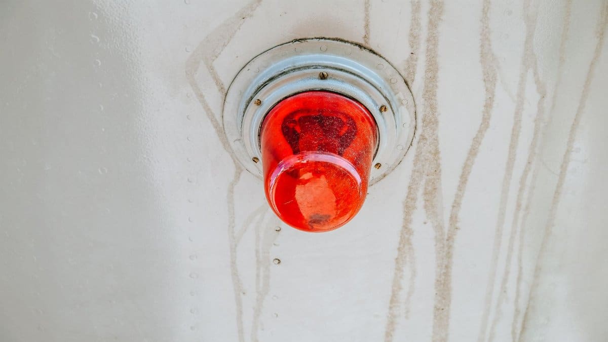 A red emergency warning light mounted on a metallic surface, often used for alerts.