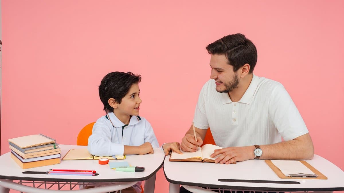 Teacher and young student engaged in study session at school desk.