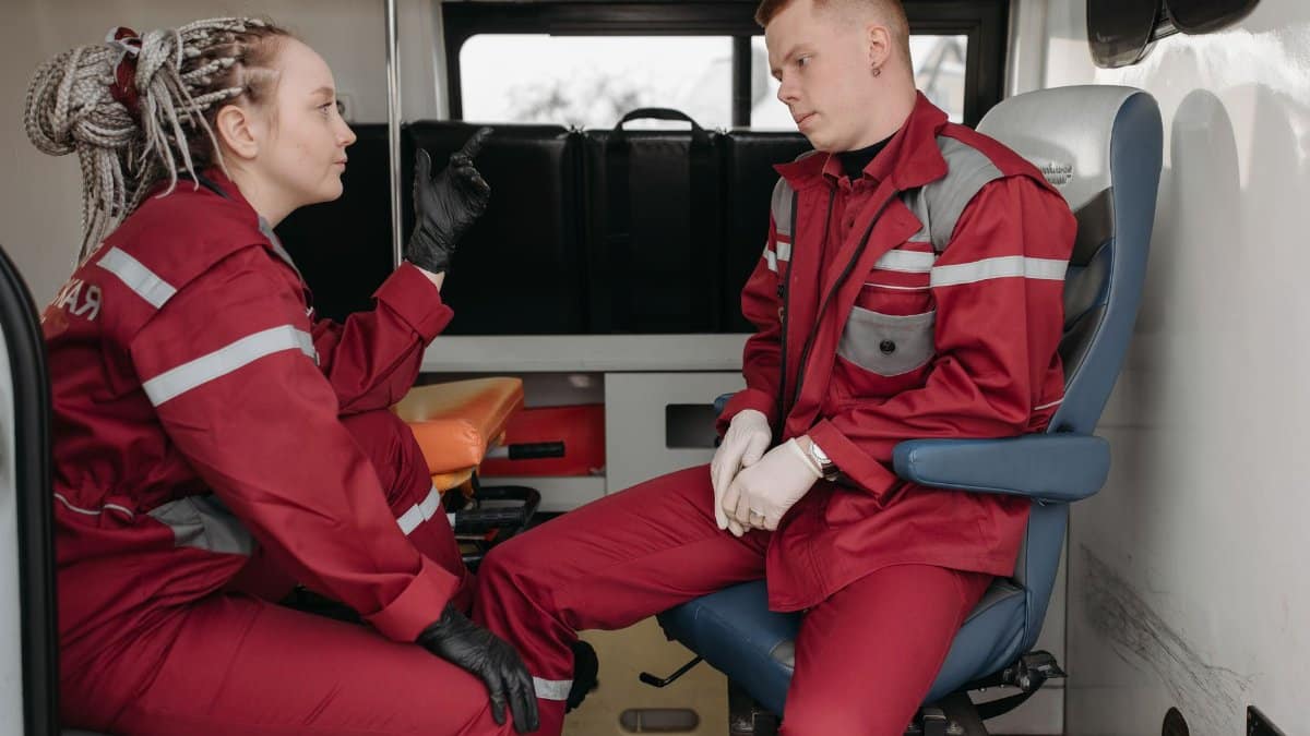 Two paramedics in uniform discussing inside an ambulance, focused on emergency healthcare.