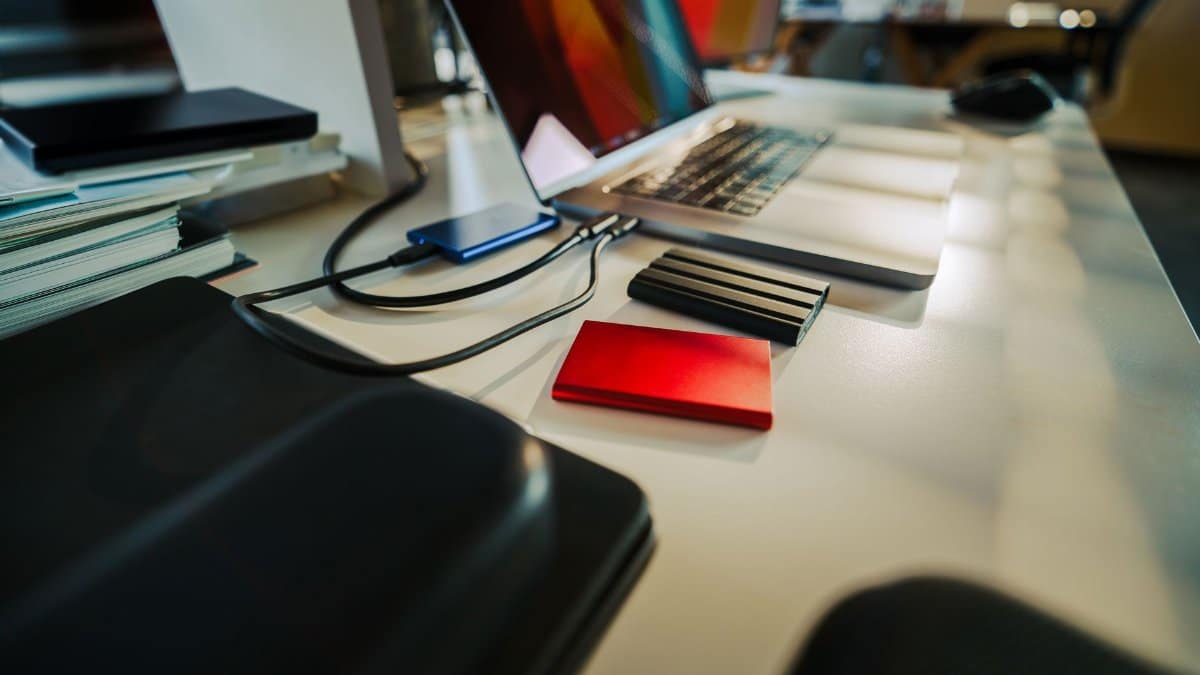 A neatly organized office desk featuring a laptop and several external hard drives, perfect for a digital workspace.