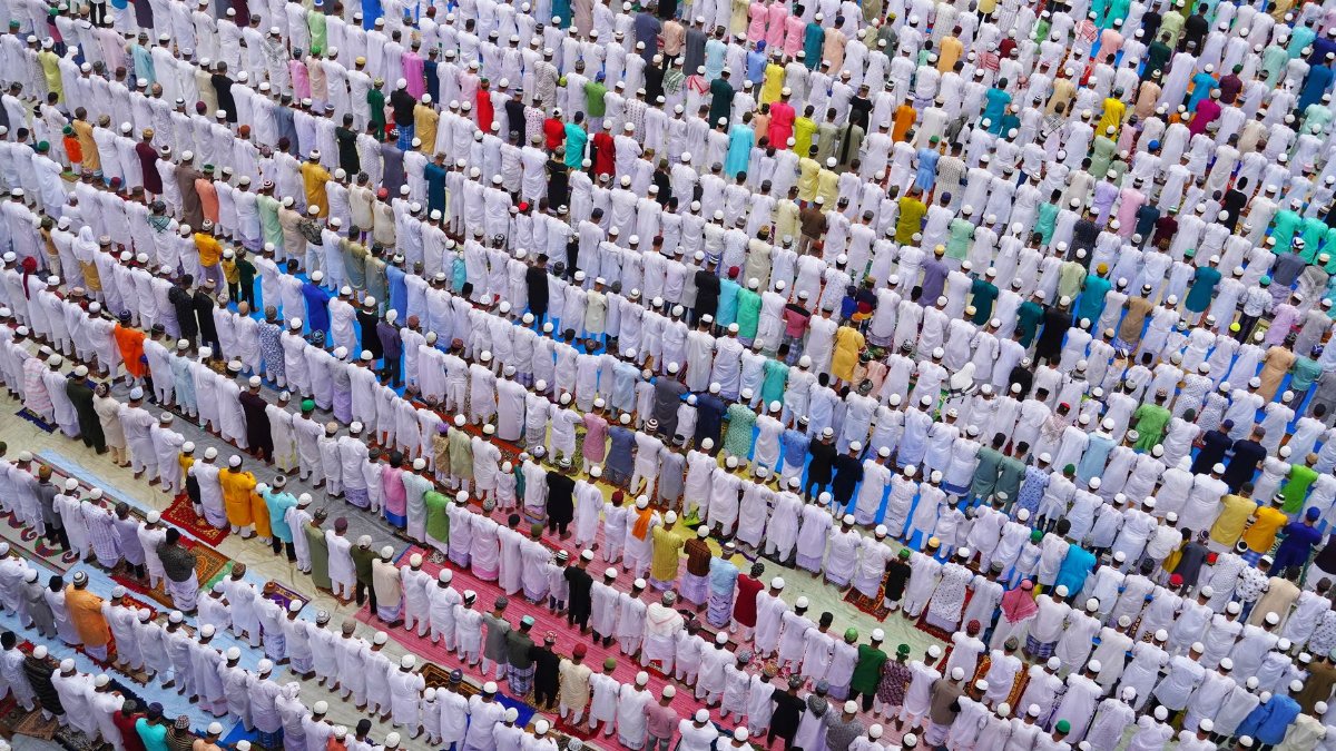 Aerial shot of a large group of people in traditional attire during a prayer in Howrah, India.
