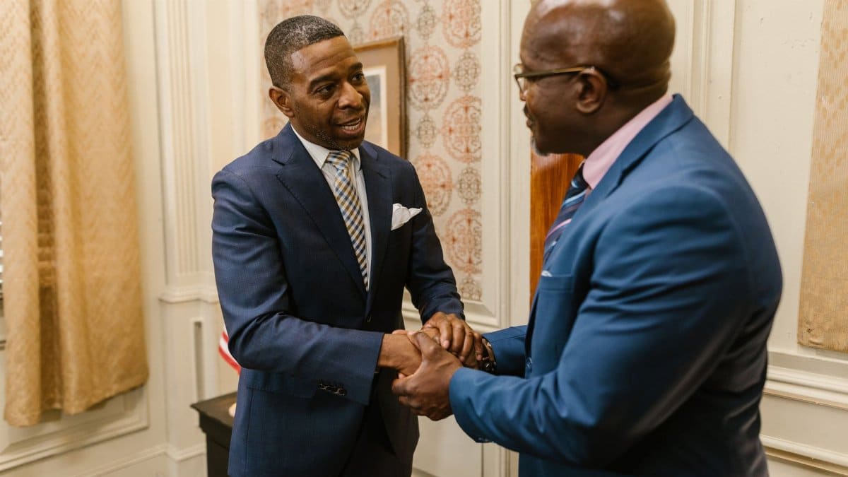 Two businessmen in suits shaking hands in an office setting, symbolizing a formal agreement.