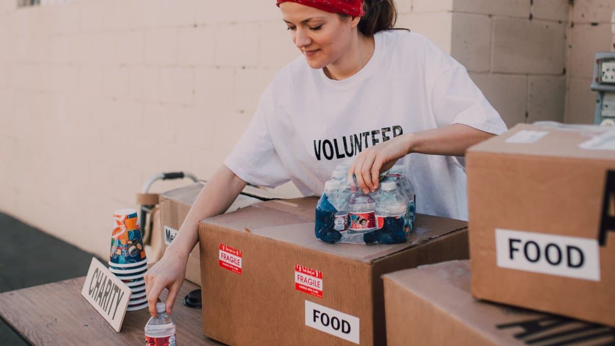 Woman volunteer sorting food and water for charity distribution at aid center.