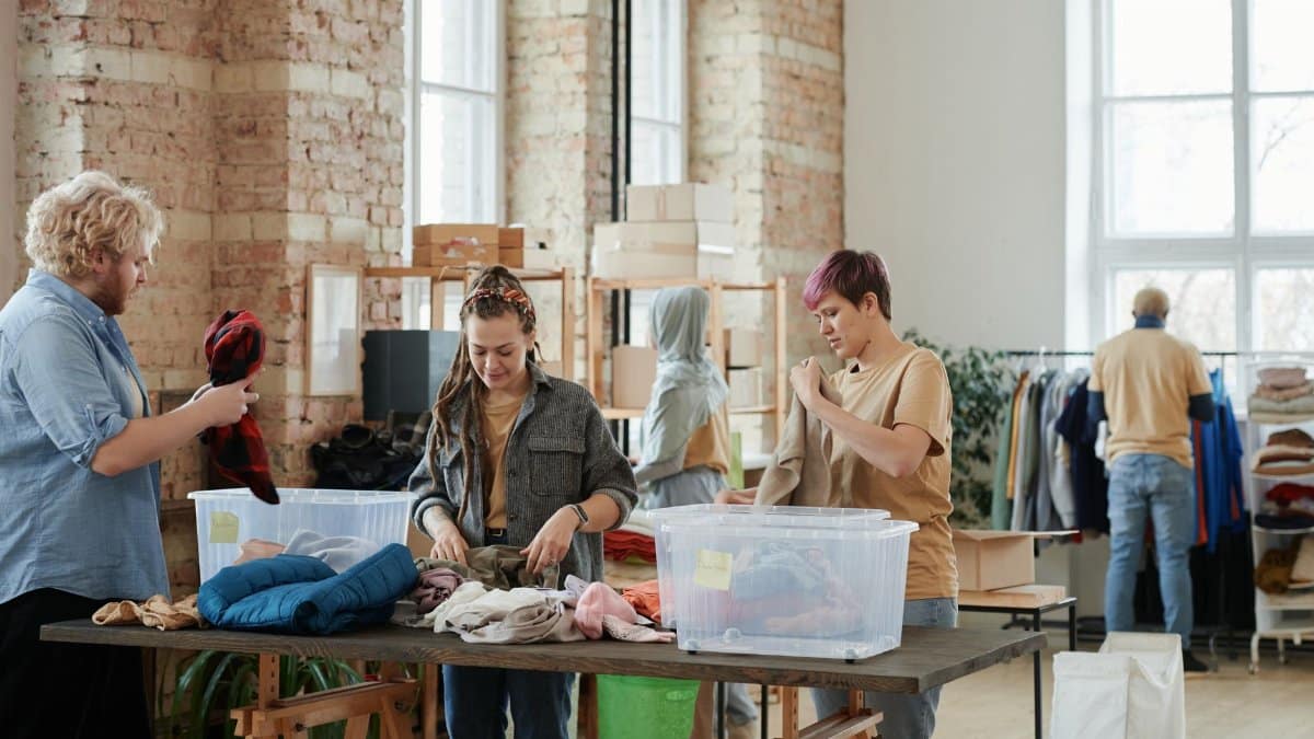 Volunteers organizing clothes in a bright, rustic donation center indoors.