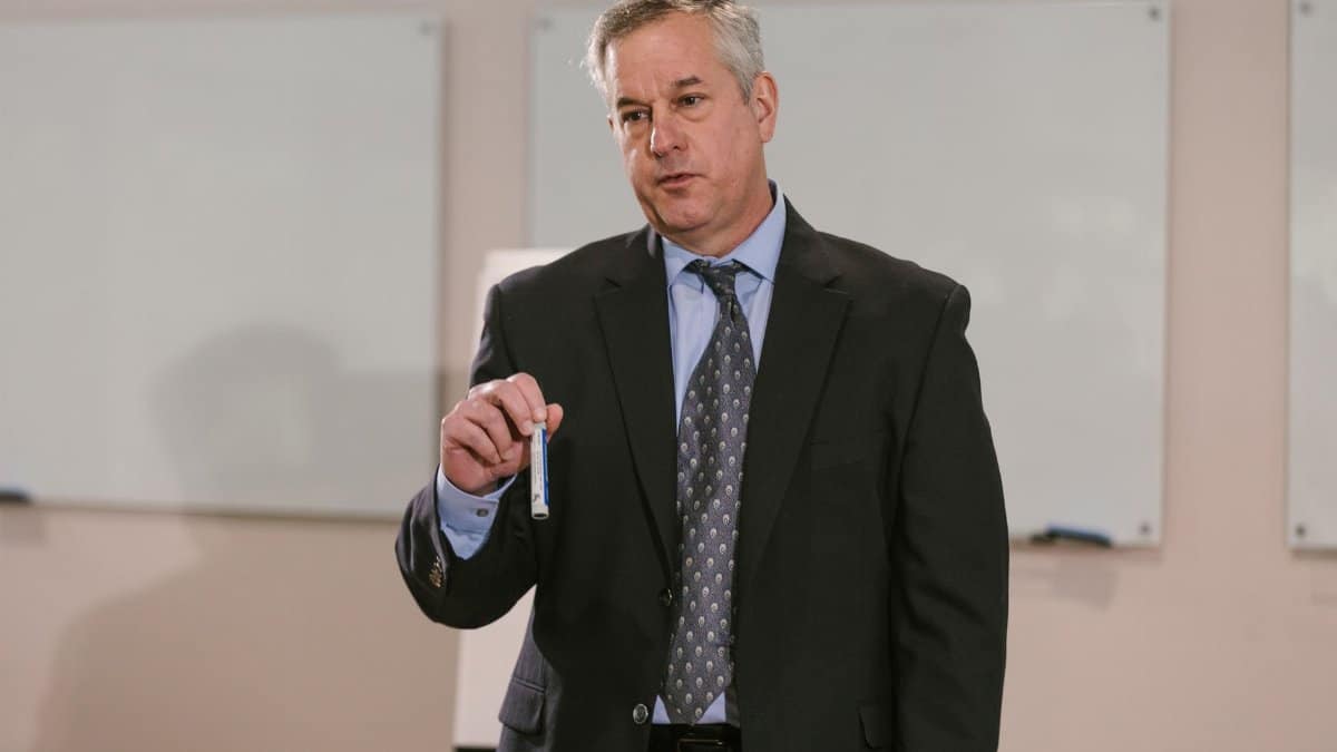 Businessman in suit presenting in office setting, emphasizing leadership and confidence.