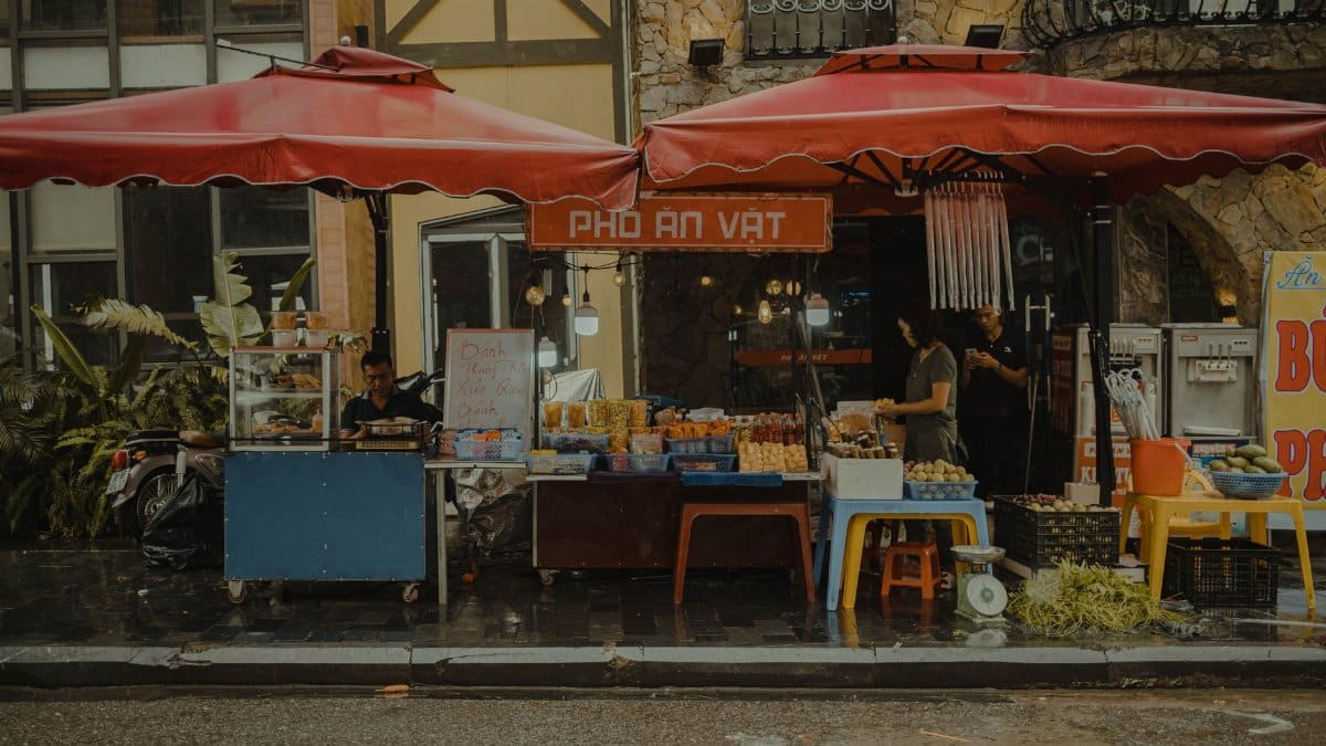 Vibrant outdoor street market featuring local vendors selling fresh produce and goods under red canopies.