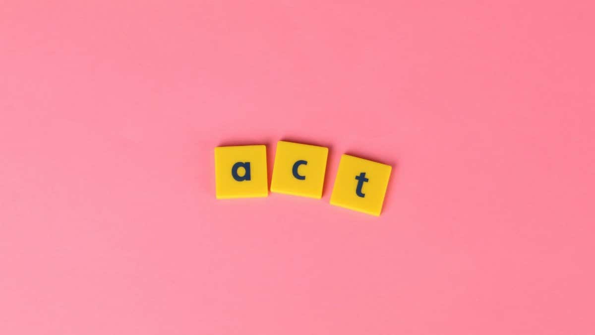 Yellow word tiles spelling 'act' on a vibrant pink background. Ideal for abstract concepts.