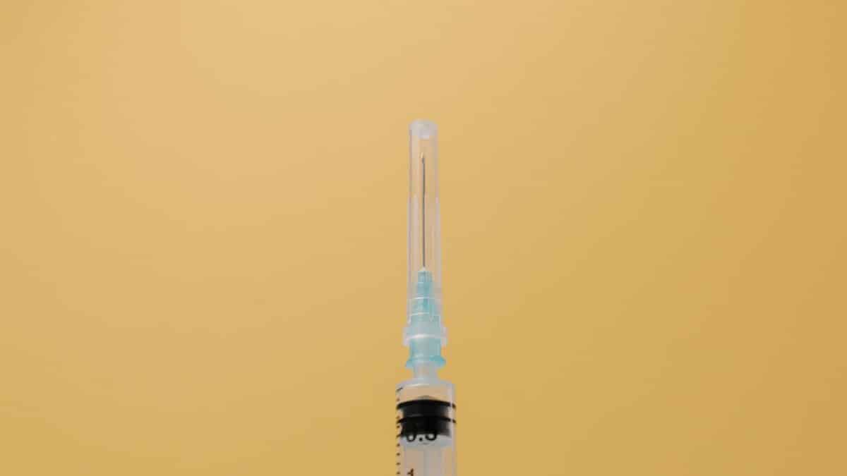 A close-up view of a syringe against a plain yellow backdrop, symbolizing healthcare.