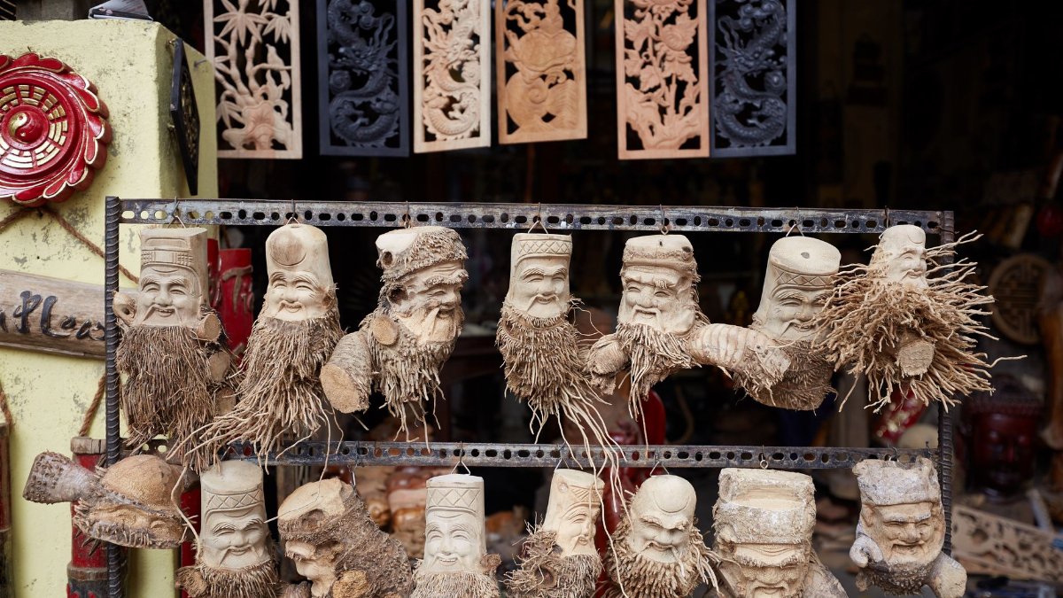 Various statuettes of unique hand carved sculptural masks made from root of bamboo placed on local market on street in city