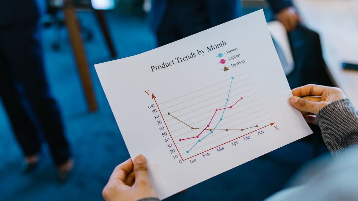 Close-up of hands holding a product trend chart in a corporate office setting.
