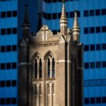 Close-up of a historic church tower against modern skyscrapers in downtown Houston, Texas.