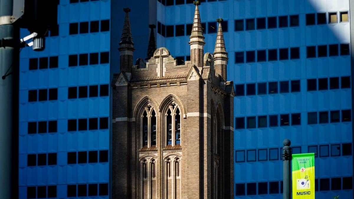 Close-up of a historic church tower against modern skyscrapers in downtown Houston, Texas.