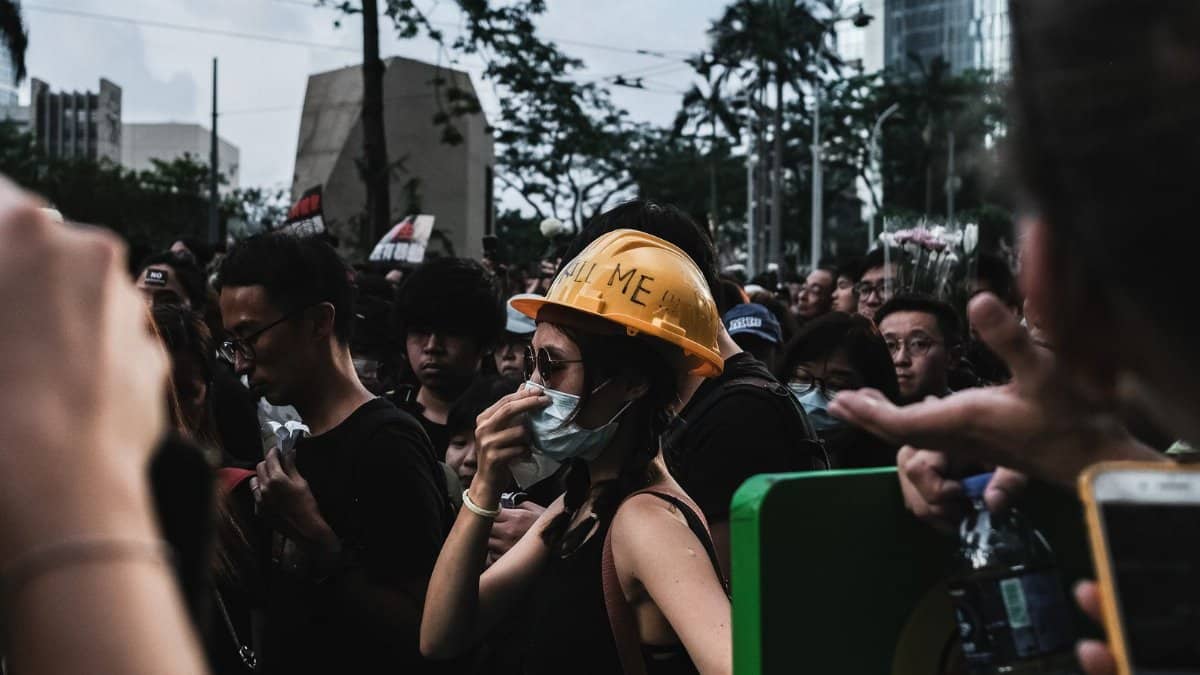Crowd of protesters in Hong Kong with masks and helmets, highlighting unity and activism.