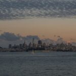 Beautiful view of San Francisco skyline with tranquil waters and a dramatic sunset sky.