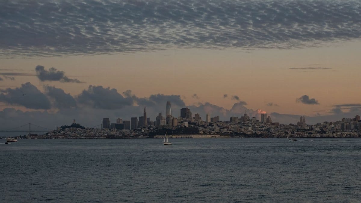 Beautiful view of San Francisco skyline with tranquil waters and a dramatic sunset sky.