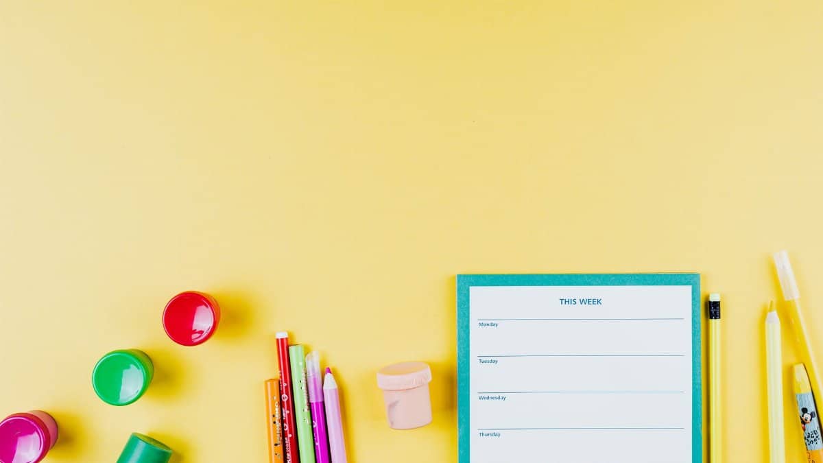 Flat lay of colorful school supplies on a yellow background with planner