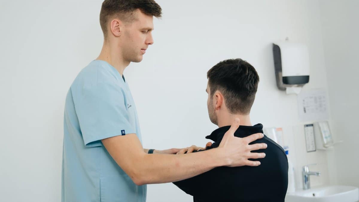 Physiotherapist working with a patient in a clinical setting, focusing on shoulder therapy.