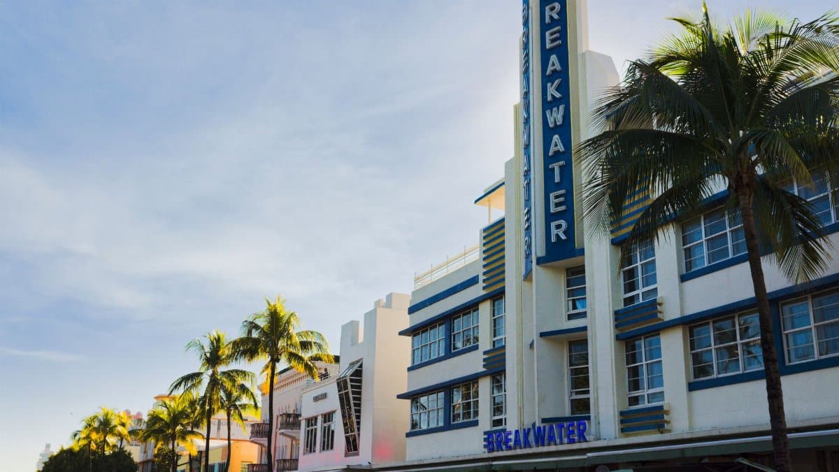 Art Deco Breakwater Hotel with palm trees in Miami Beach. Iconic South Beach architecture under a clear sky.