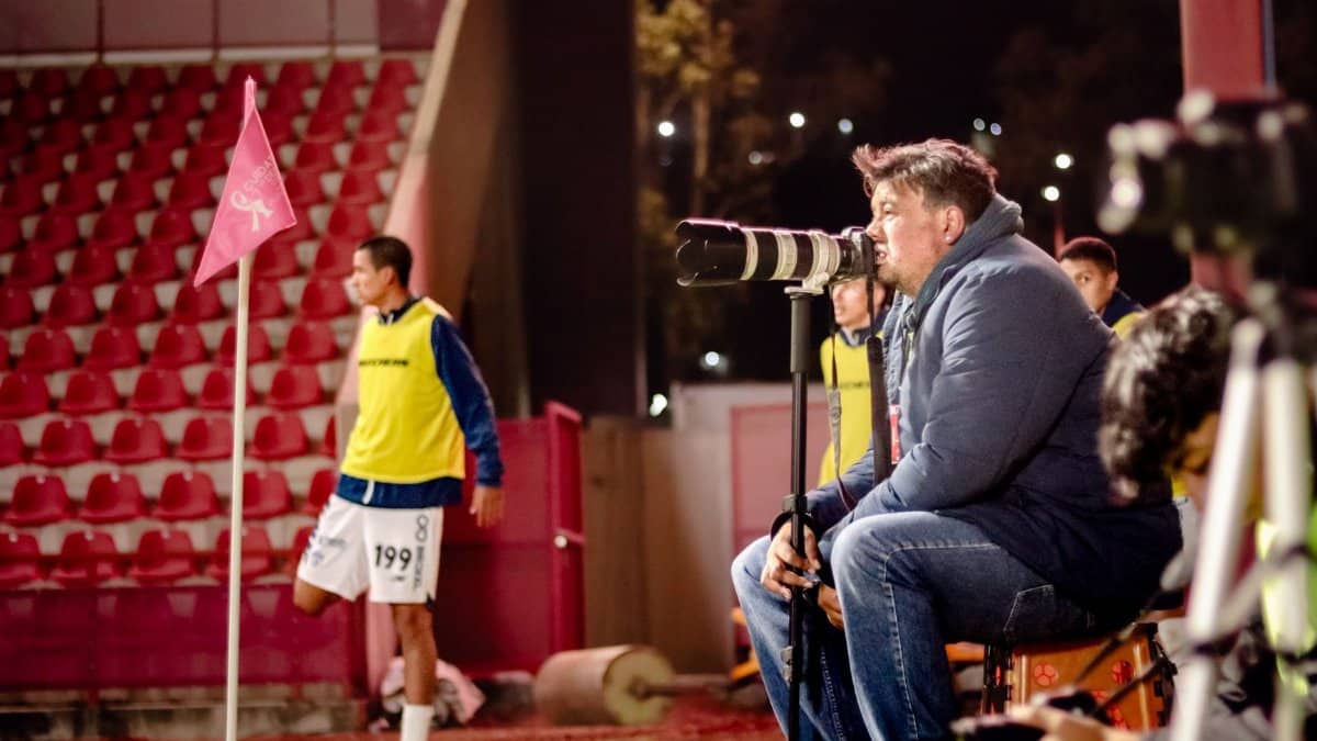 Soccer coach intensely watches game at night stadium, focused on strategy.