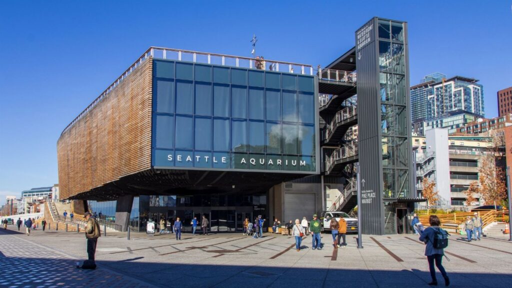 The front entrance of Seattle Aquarium on a sunny day with visitors outside.