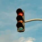 A traffic light with red signal set against a blue sky, signifying stop in urban streets.