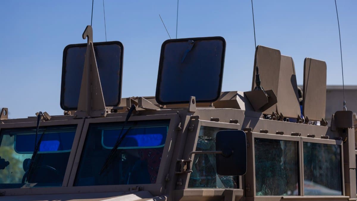 Close-up of military vehicle showing armored details under a clear sky.