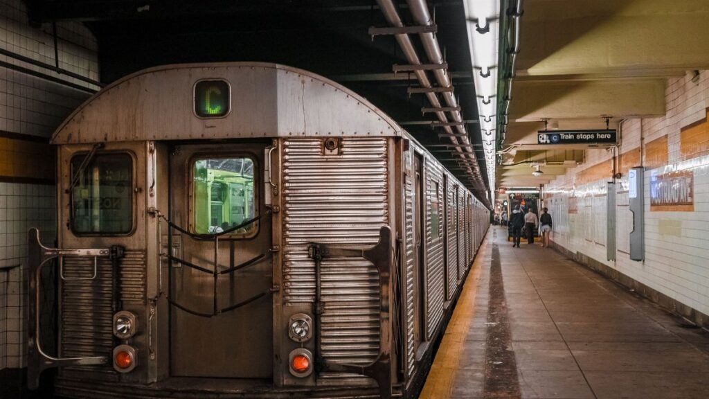 A subway train parked at an urban subway station platform with passengers walking by.